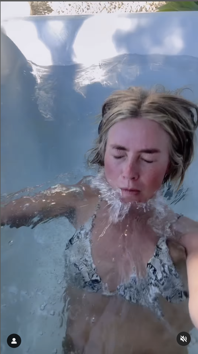 A person in a bikini swimming underwater with her eyes closed