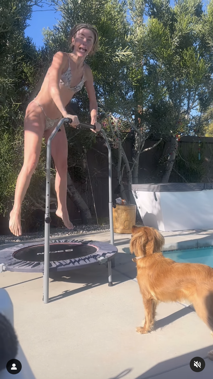 Julianne Hough exercises on the trampoline outside by the pool, while her dog watches her carefully