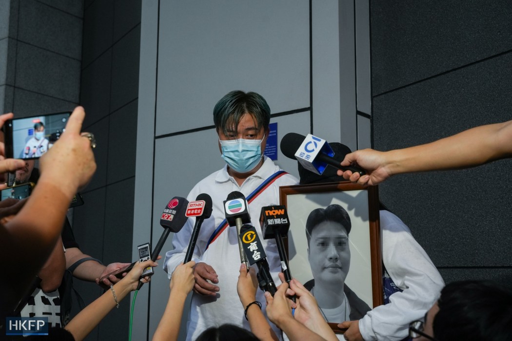 The brother of a man who died after being shot by the police holds a picture of his dead brother outside the police headquarters in Wan Chai, on September 22, 2024. Photo: Kyle Lam/HKFP.